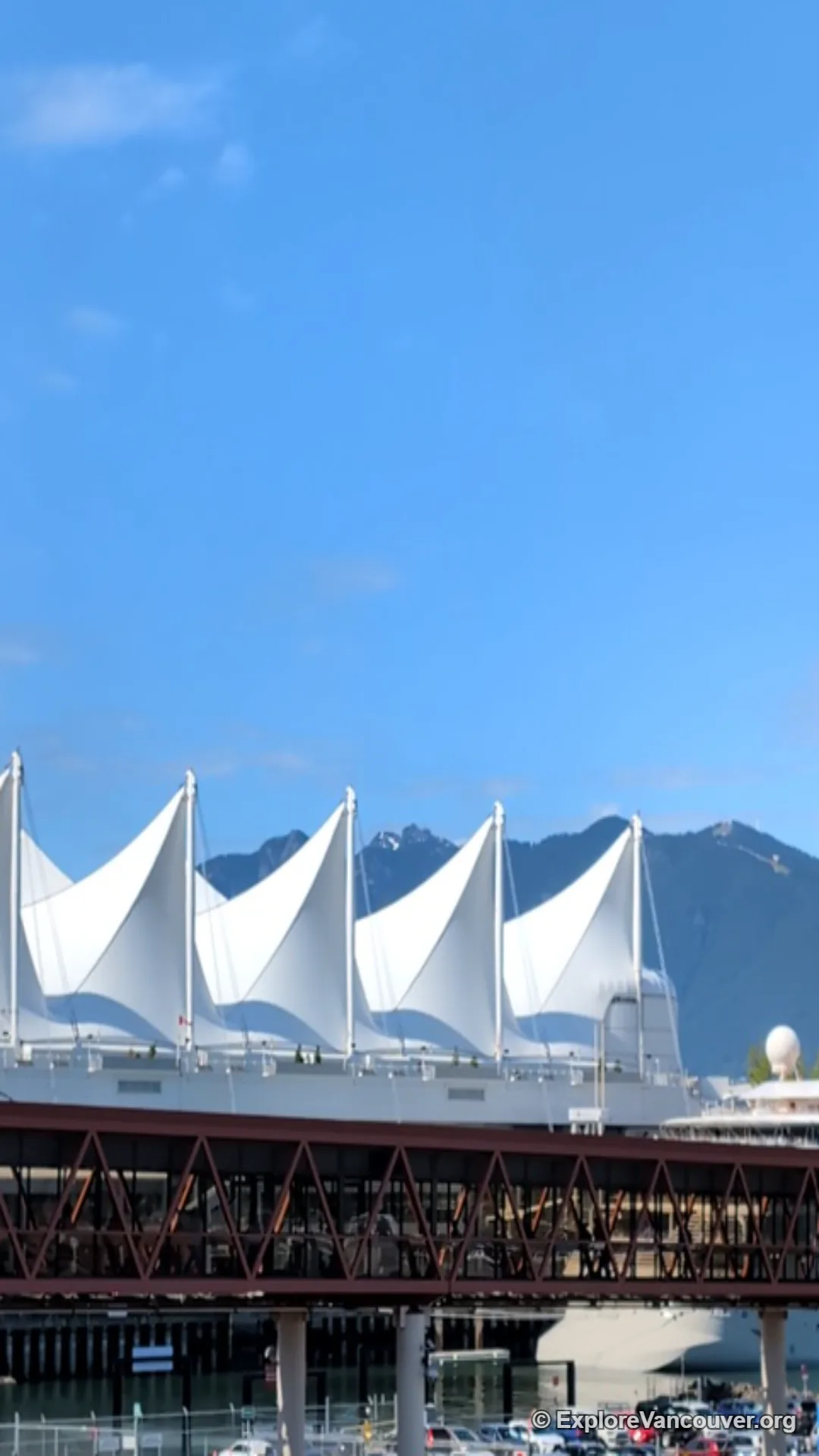 Vertical view along the west promenade at Canada Place, with the harbour and North Shore mountains visible in the distance