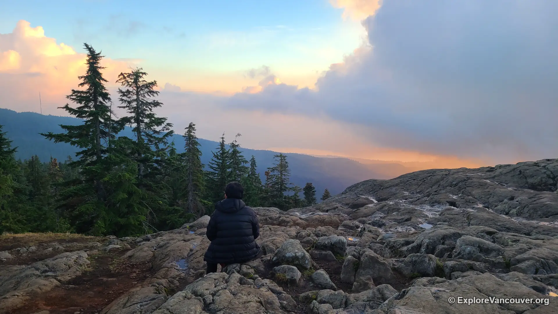 A hiker sitting at the Dog Mountain summit overlooking the view