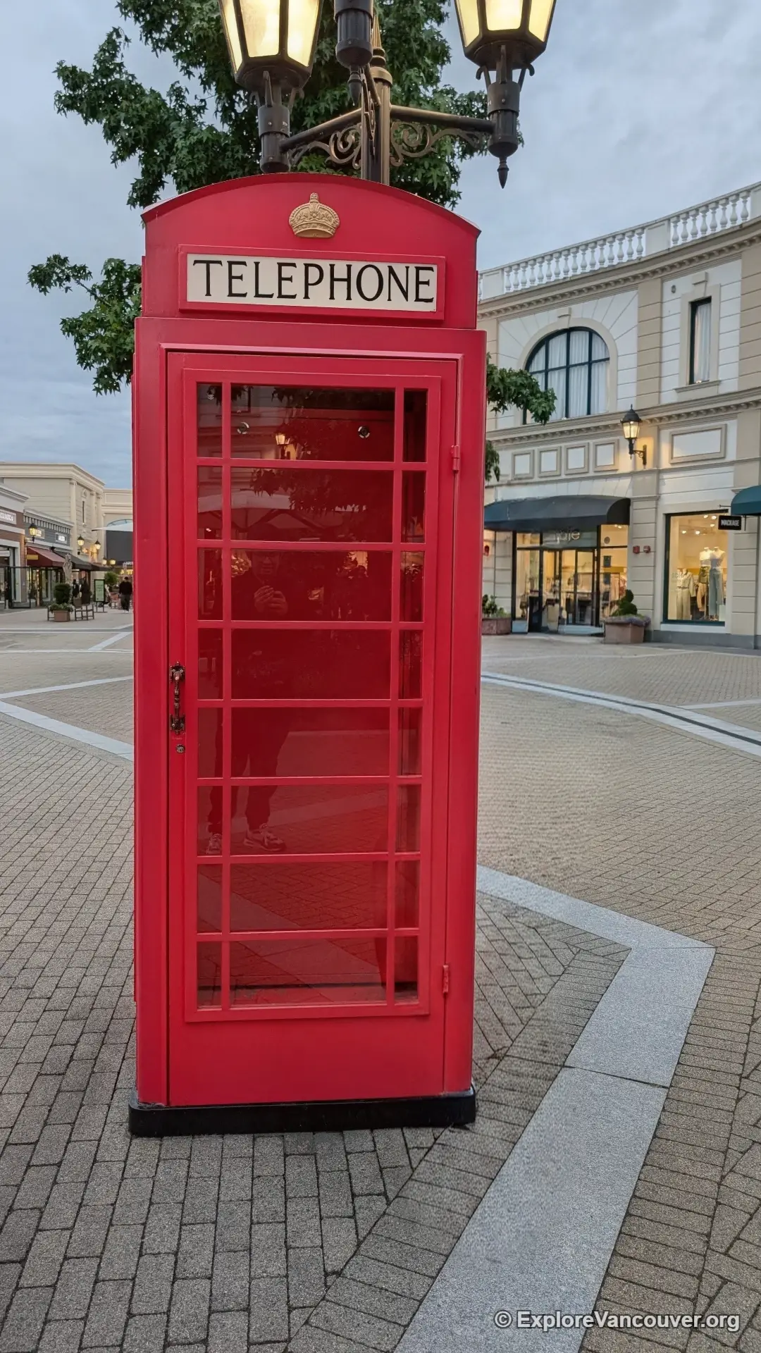 Red British style telephone booth along a walkway at McArthurGlen Designer Outlet